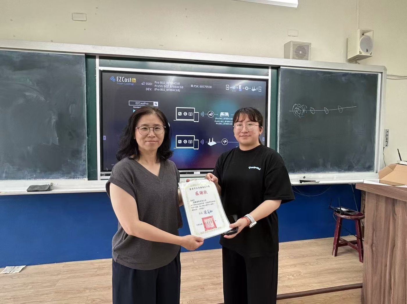 竹橋國中老師手持感謝狀，教室內架設 EZCast Pro 螢幕